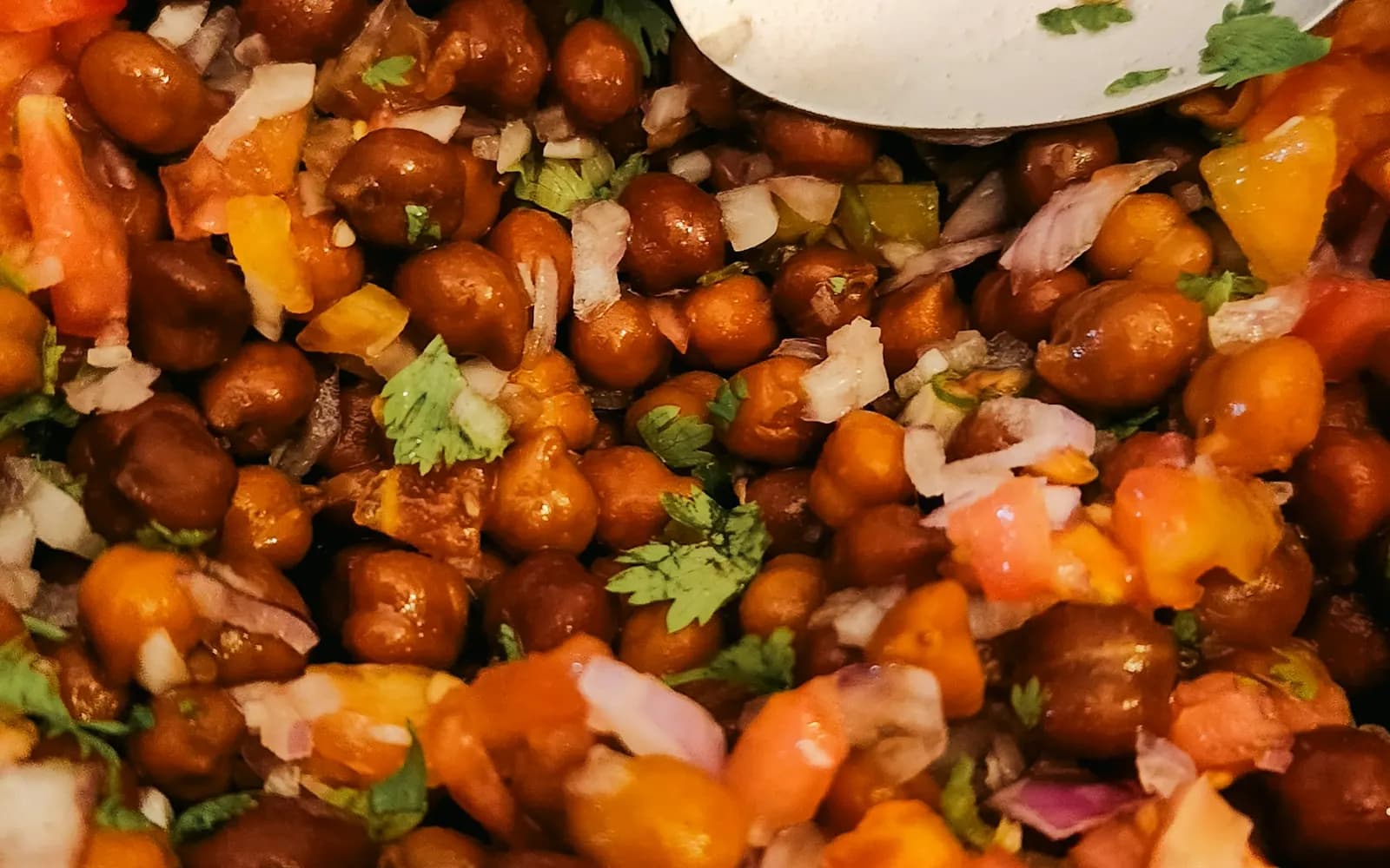 Close-up of kala chana chaat with tomato, onion and coriander