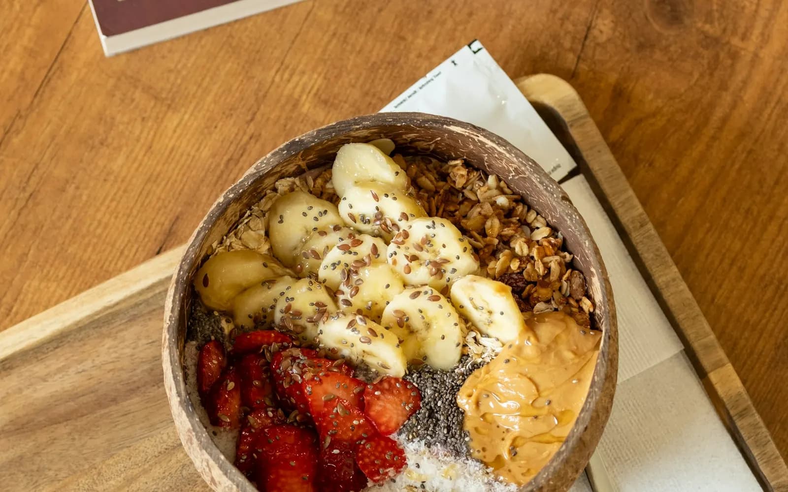 A bowl of oats topped with banana, strawberries, seeds and peanut butter